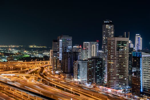 Vibrant night view of Dubai's modern skyline with illuminated skyscrapers and bustling highways.
